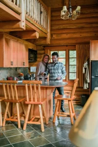 A happy laughing couple stood in the kitchen of a cabin at Alpine Village Jasper