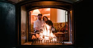 A romantic couple snuggled on a couch watching their log fireplace in their alpine village cabin
