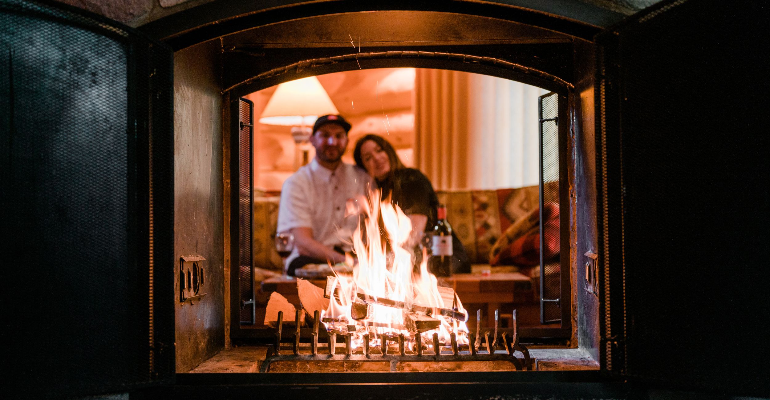 A romantic couple snuggled on a couch watching their log fireplace in their alpine village cabin