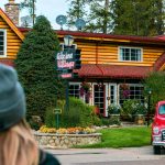 A woman outside in a hat looking at the Alpine Village main building