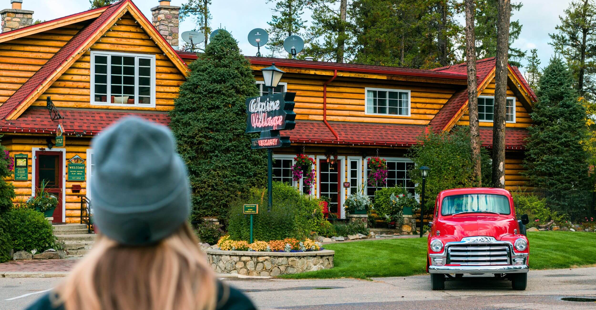 A woman outside in a hat looking at the Alpine Village main building