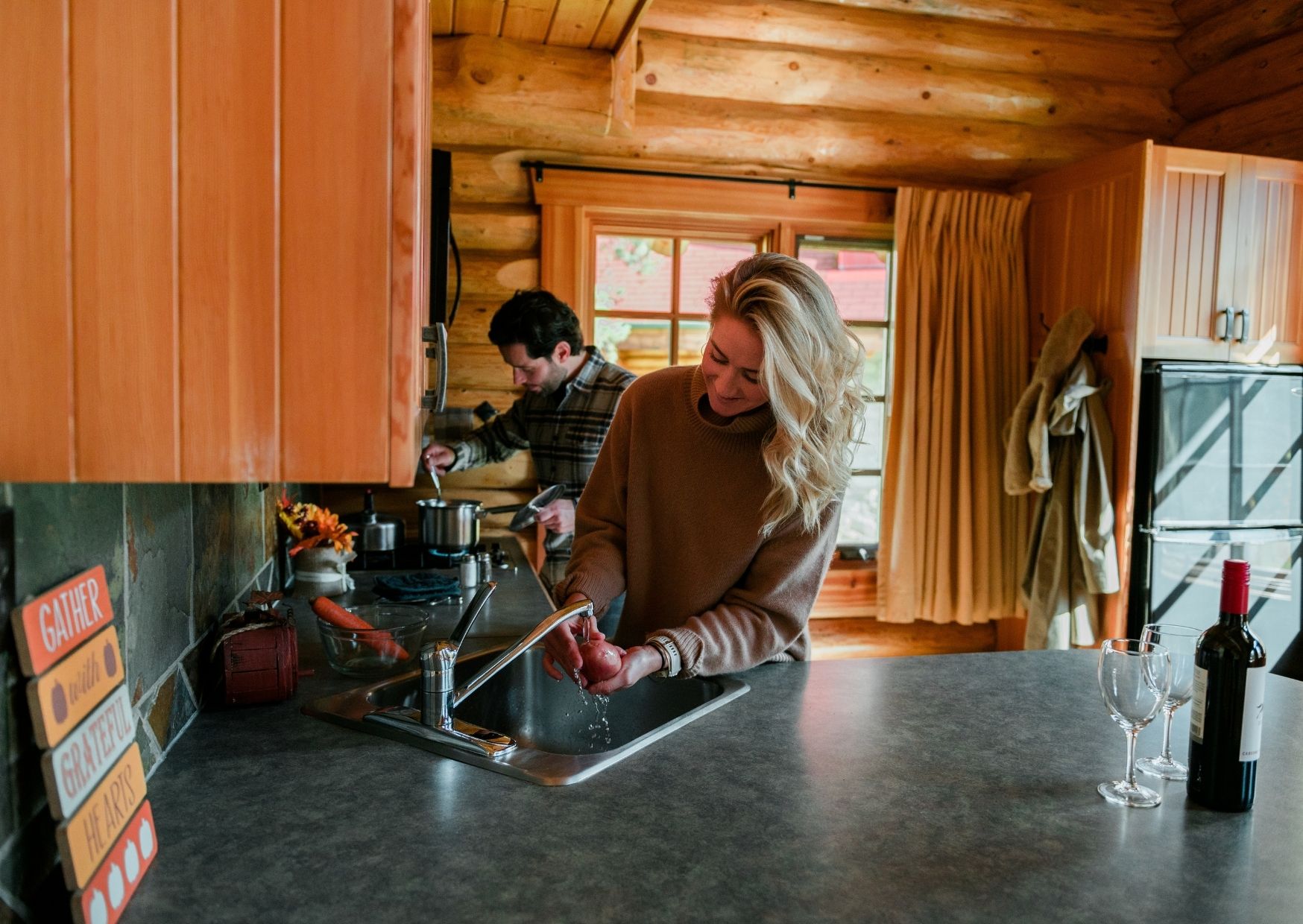 A happy couple work on preparing food together in an alpine village cabin