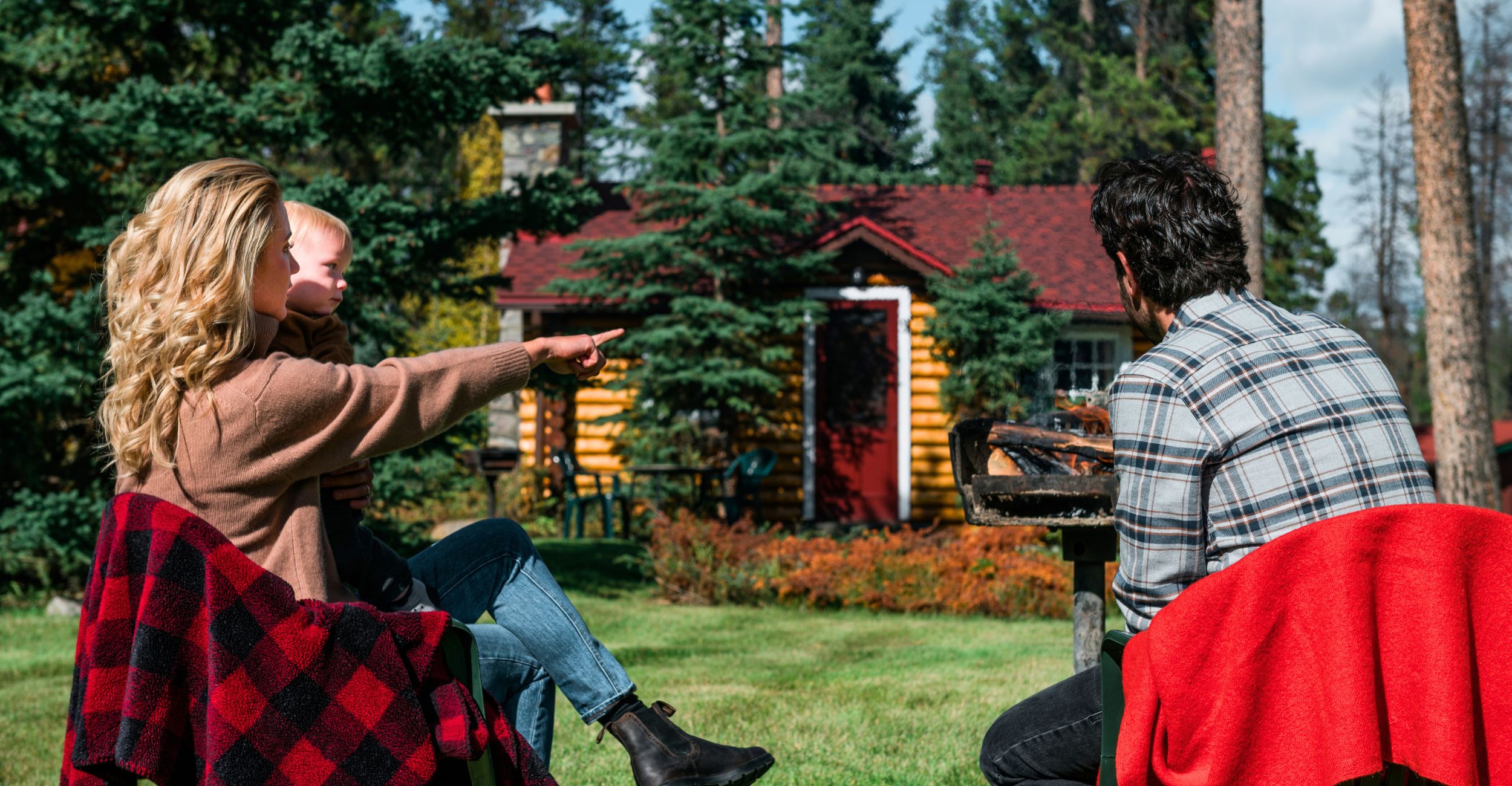 A family at Alpine Village Jasper having a BBQ outside and pointing at something out of frame