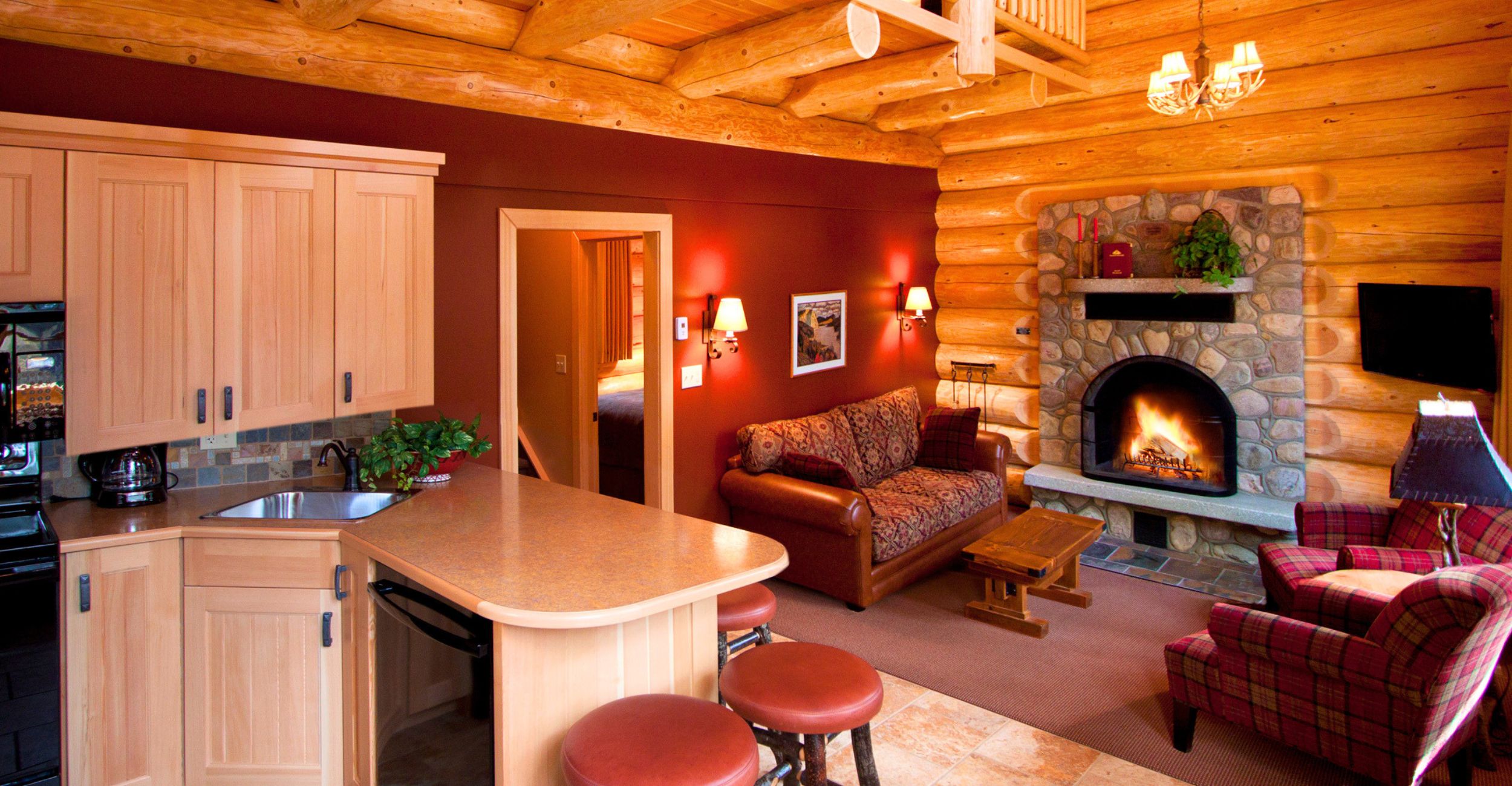 Interior of a deluxe family cabin at Alpine Village, showing a fireplace, seats, and the kitchen.
