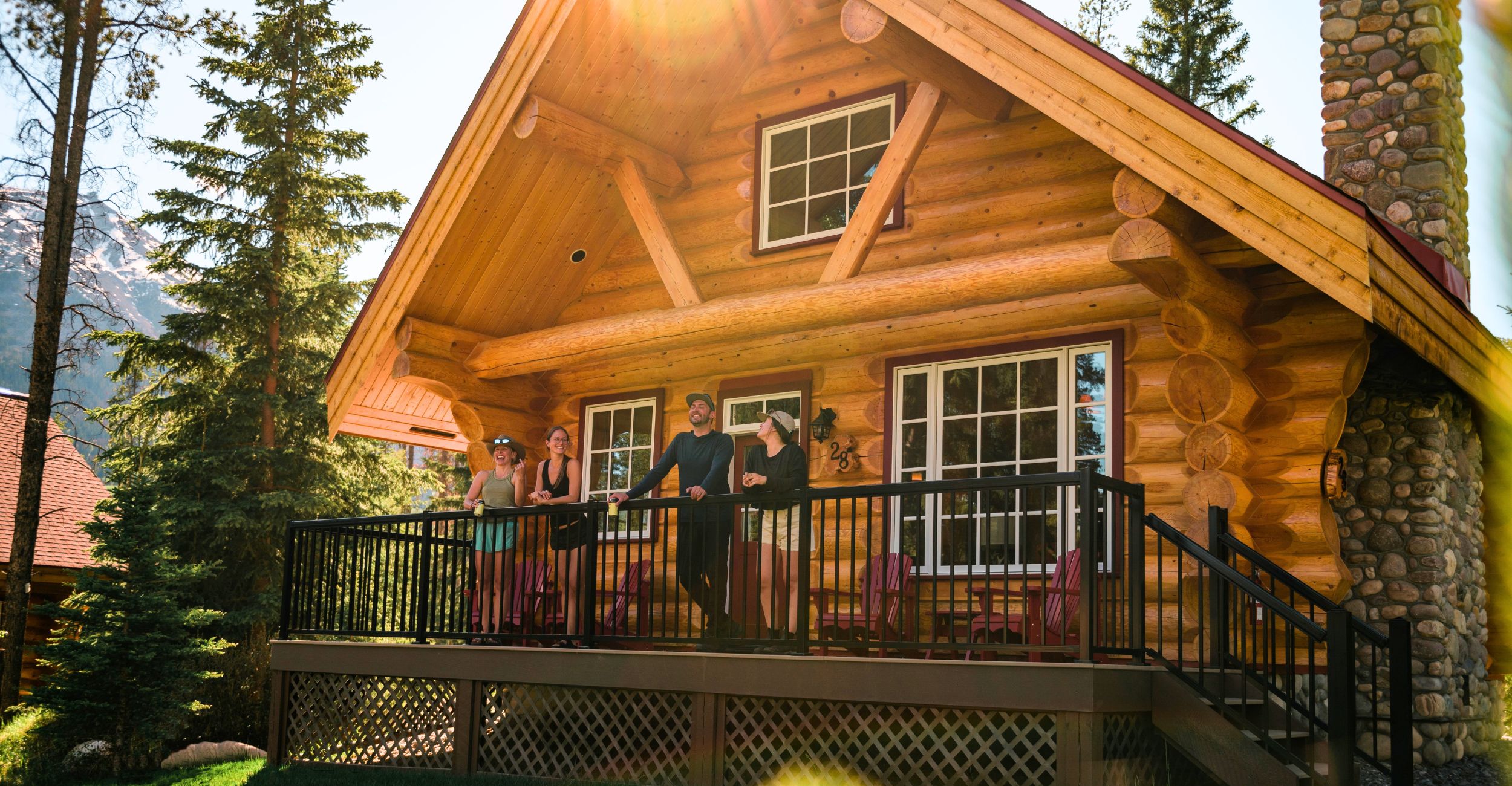 Happy people talking together looking over their cabin deck at Alpine Village Jasper